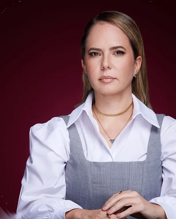 Dra. Benedita Machado sentada à mesa, de camisa branca e colete cinza